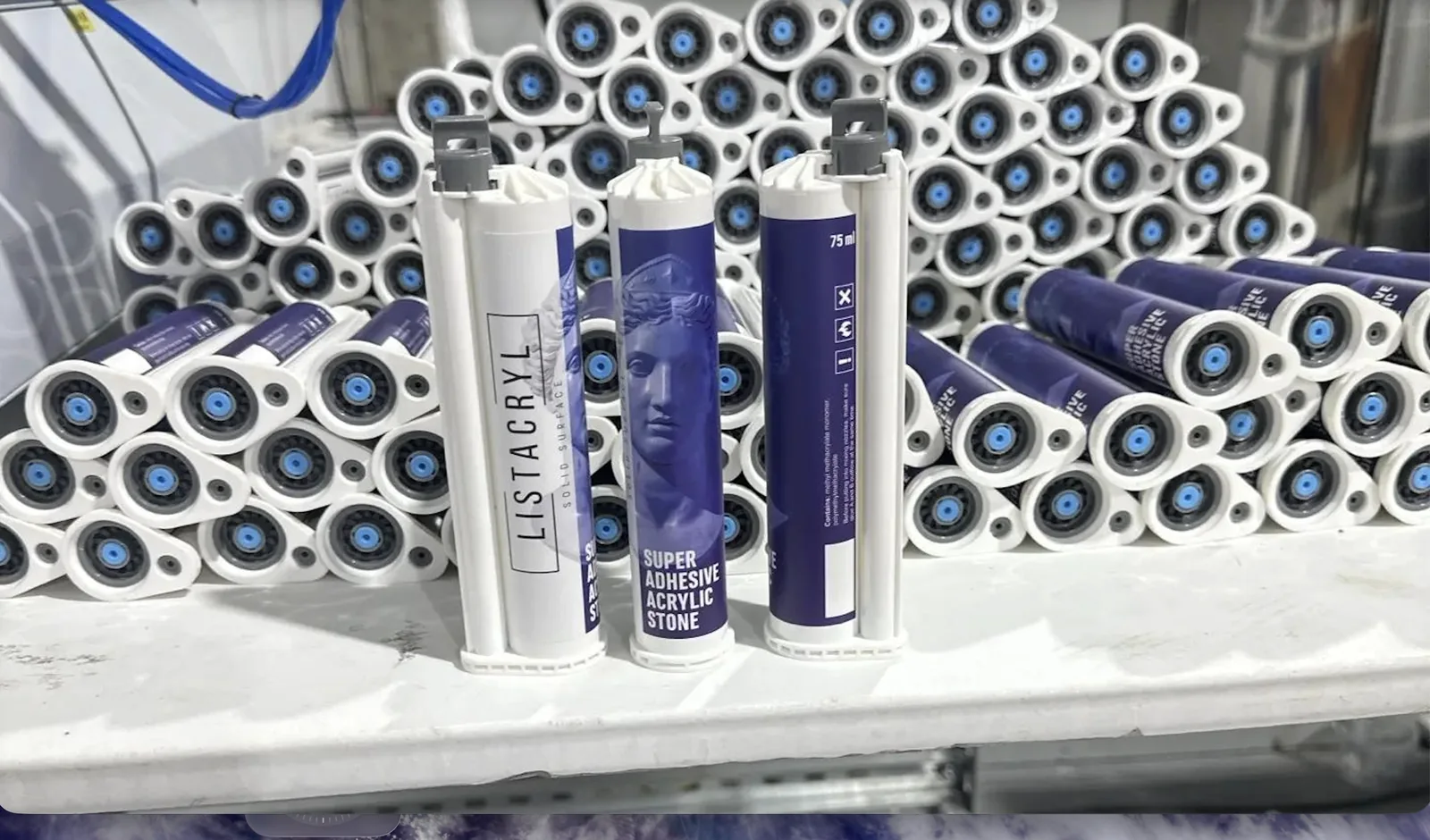 LISTACRYL Super Adhesive Acrylic Stone cartridges at the packing area: three cartridges on the bench in front of a finished batch